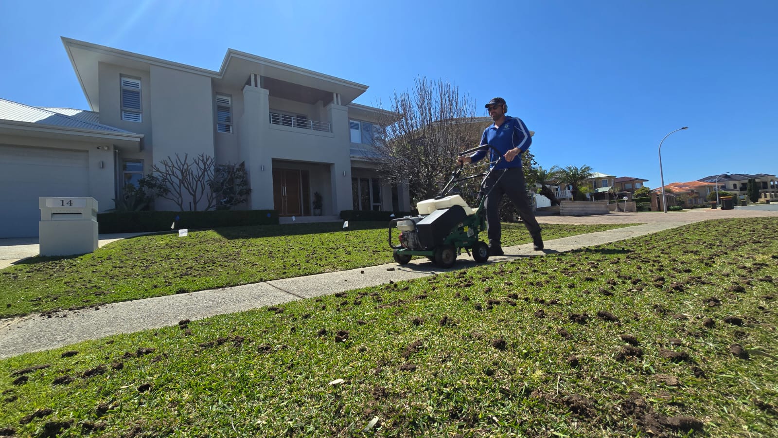Premier Lawns operator running a core aerator across a lush Perth lawn